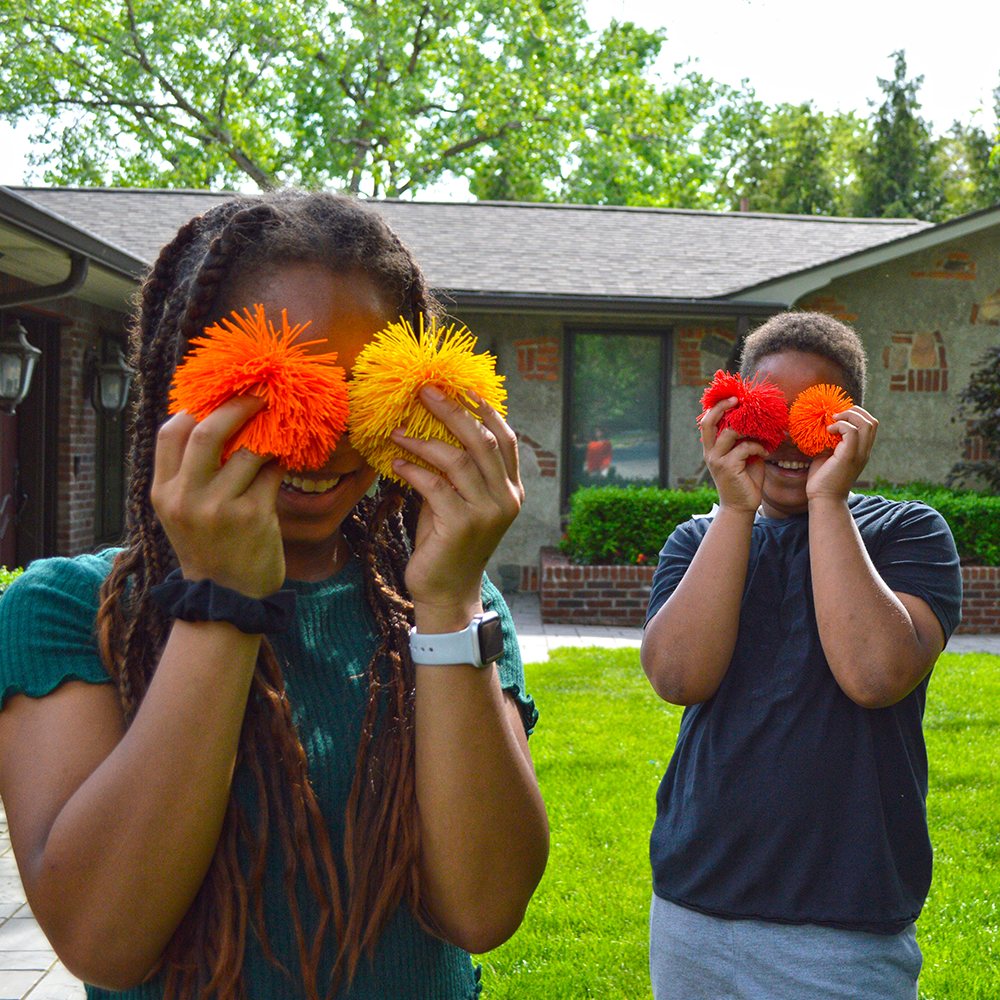 Kids holding Koosh balls up like goggles