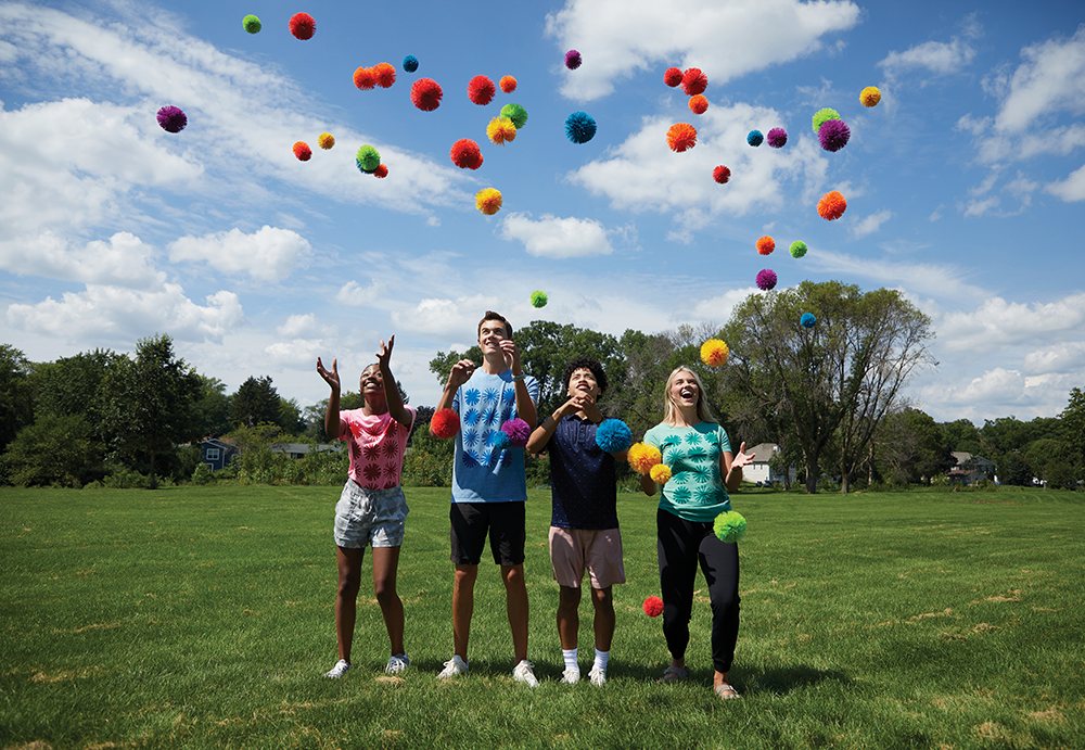 Kids throwing Koosh balls into the air in a field